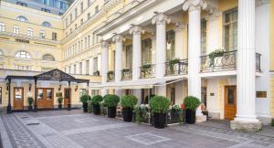 a building with a row of potted plants in a courtyard at The State Hermitage Museum Official Hotel in Saint Petersburg