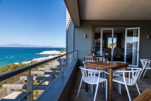 a balcony with tables and chairs and the ocean at Tintswalo Boulders in Simonʼs Town