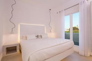 Un dormitorio blanco con una cama blanca y una ventana en Art Hotel Santorini en Pyrgos