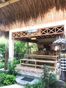 un restaurante con banco de madera y techo de paja en Meno Madia Bungalows, en Gili Meno
