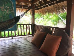 a hammock on a porch with two pillows at Meno Madia Bungalows in Gili Meno