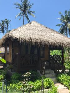a small hut with a straw roof with palm trees at Meno Madia Bungalows in Gili Meno