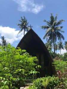 a small hut with palm trees in the background at Meno Madia Bungalows in Gili Meno