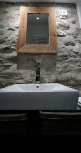Auzat的住宿－la feda gîte Pyrénées Ariégeoises，浴室的盥洗盆和石墙上的镜子