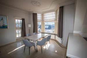 a dining room with a table and chairs and windows at Fletcher Hotel Restaurant Marijke in Bergen