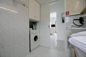 a white laundry room with a washing machine and a sink at Ostria Seaside Home in Almirida