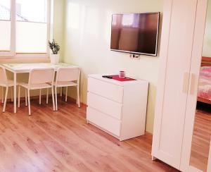 a room with a table and a tv on a wall at Irmos Apartamentai salia Klaipedos in Toleikiai