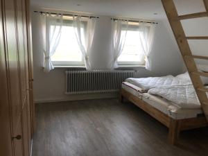 a bedroom with a bed and two windows at Ferienhaus Nordseerobbe in Friedrichskoog
