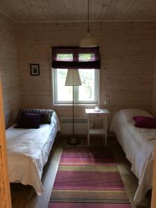 two beds in a small room with a window at Ollilan tupa Joensuun lähellä in Ylämylly