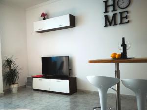 een woonkamer met een tv en een tafel met stoelen bij Apartment Granada 302 Pool&Beach in Torrevieja