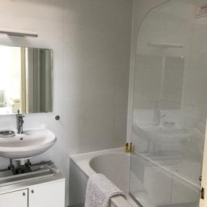 W białej łazience znajduje się umywalka, wanna i lustro. w obiekcie City Flat gegenüber Kurhaus, Zentrum Freudenstadt w mieście Freudenstadt