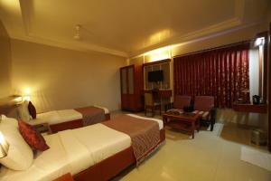 a hotel room with two beds and a couch at Hotel Green Palace in Puducherry