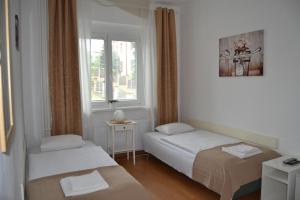 プラハにあるPension Nikaのベッド2台と窓が備わる小さな客室です。