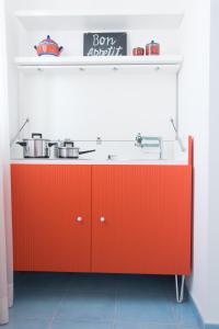 una cucina con bancone arancione con pentole e padelle di B&B Il Castello a Città di Lipari