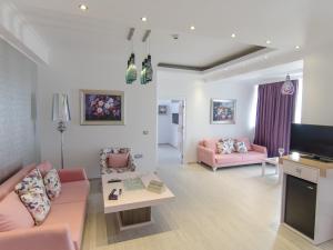 sala de estar con muebles de color rosa y TV de pantalla plana. en Phoenicia Luxury Hotel, en Mamaia Nord – Năvodari