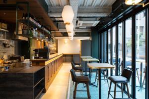 a restaurant with tables and chairs and windows at IMANO OSAKA SHINSAIBASHI HOSTEL in Osaka