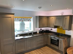 Salt Pot Cottage في سكيبتون: مطبخ بدولاب رمادي ومغسلة