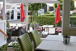 un patio al aire libre con mesas, sillas y sombrillas en Landhotel Gillenfelder Hof, en Gillenfeld