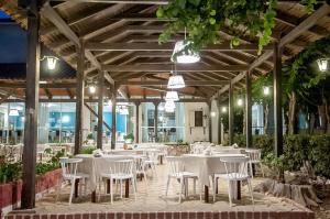 a restaurant with white tables and chairs in a building at Mimoza Beach in Argasi