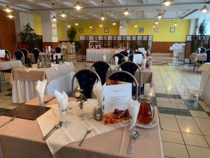 un comedor con mesas con manteles y sillas blancas en Hotel Patriot, en Vranov nad Topľou