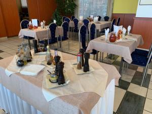 uma fila de mesas num restaurante com toalha de mesa branca em Hotel Patriot em Vranov nad Topľou