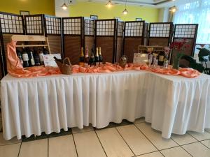 Una mesa blanca con botellas de vino. en Hotel Patriot, en Vranov nad Topľou