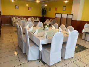 uma sala de jantar com mesas brancas e cadeiras brancas em Hotel Patriot em Vranov nad Topľou