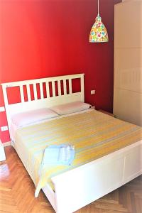ミラノにあるYouhome Millelire Apartmentの赤い壁のベッドルーム1室(白いベッド1台付)