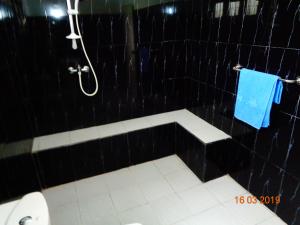 a black tiled bathroom with a shower and a toilet at Solal Villa in Aluthgama