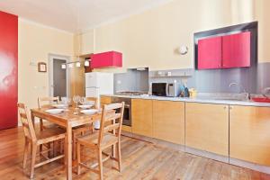 eine Küche mit einem Holztisch und eine Küche mit roten Schränken in der Unterkunft Buenos Aires Shopping Flat in Mailand