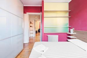 ein Schlafzimmer mit einem weißen Bett und einer rosa Wand in der Unterkunft Buenos Aires Shopping Flat in Mailand