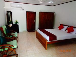 - une chambre avec un lit doté d'oreillers rouges et d'une chaise dans l'établissement Solal Villa, à Aluthgama