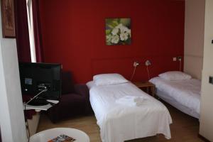 a hotel room with two beds and a television at Hotel Saint Vincent in Poeldijk