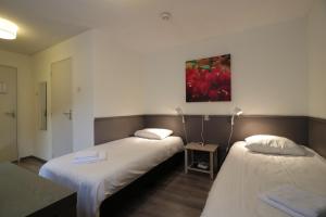 Habitación con 2 camas y una pintura en la pared. en Hotel Saint Vincent en Poeldijk