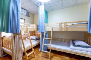 a room with three bunk beds with blue curtains at Guesthouse Nagonde in Kanazawa