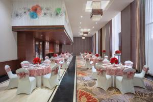 - une salle de banquet avec des tables, des chaises blanches et des fleurs rouges dans l'établissement Fortune Avenue, Jalandhar - Member ITC's Hotel Group, à Jalandhar