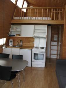 una cocina con electrodomésticos blancos y una mesa con sillas. en Vikær Strand Camping & Cottages, en Diernæs