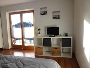 1 dormitorio con 1 cama y TV en un estante en Bergblick und See, en Bernau am Chiemsee