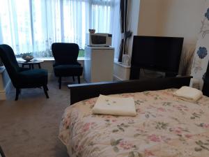 a bedroom with a bed and two chairs and a television at Welcome Holiday Flats in Skegness