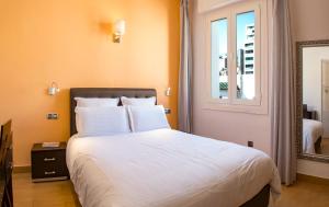 - une chambre avec un grand lit blanc et une fenêtre dans l'établissement Appartements Rabat Balima Harcourt, à Rabat