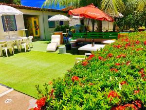 a garden with tables and chairs and red flowers at Ótima Localização casa, 7 quartos-Porto de Galinhas 900m piscinas naturais in Porto De Galinhas