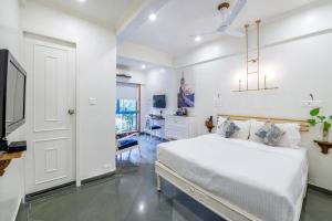 una camera da letto bianca con un letto e una scrivania di Hotel Kemps Corner a Mumbai