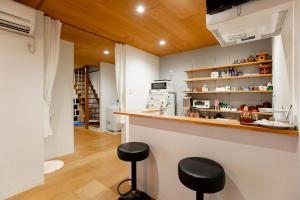 a kitchen with a counter and stools in a room at Guesthouse Nagonde in Kanazawa