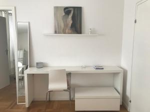 a white desk with a chair and a painting on the wall at Small Home in Freudenstadt