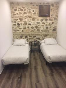 2 letti in una camera con parete in pietra di Apartamento Tolaitola a Toledo
