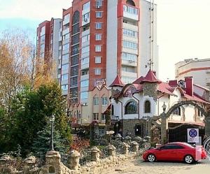 une voiture rouge garée devant un bâtiment dans l'établissement СВІТЛО ЦІЛОДОБОВО Просторі апартаменти біля гідропарку Топільче, à Ternopil