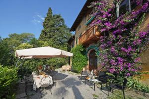 a patio with a table and purple flowers next to a building at Villa FiordiSole in Salò