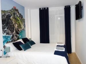 1 dormitorio con 1 cama blanca grande con almohadas azules en La Concordia, en Bilbao
