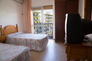 a hotel room with two beds and a balcony at Hostal Susi in Peñíscola