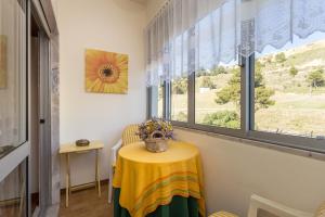 a table with a yellow table cloth in a room with a window at Casa da Praia in Costa da Caparica